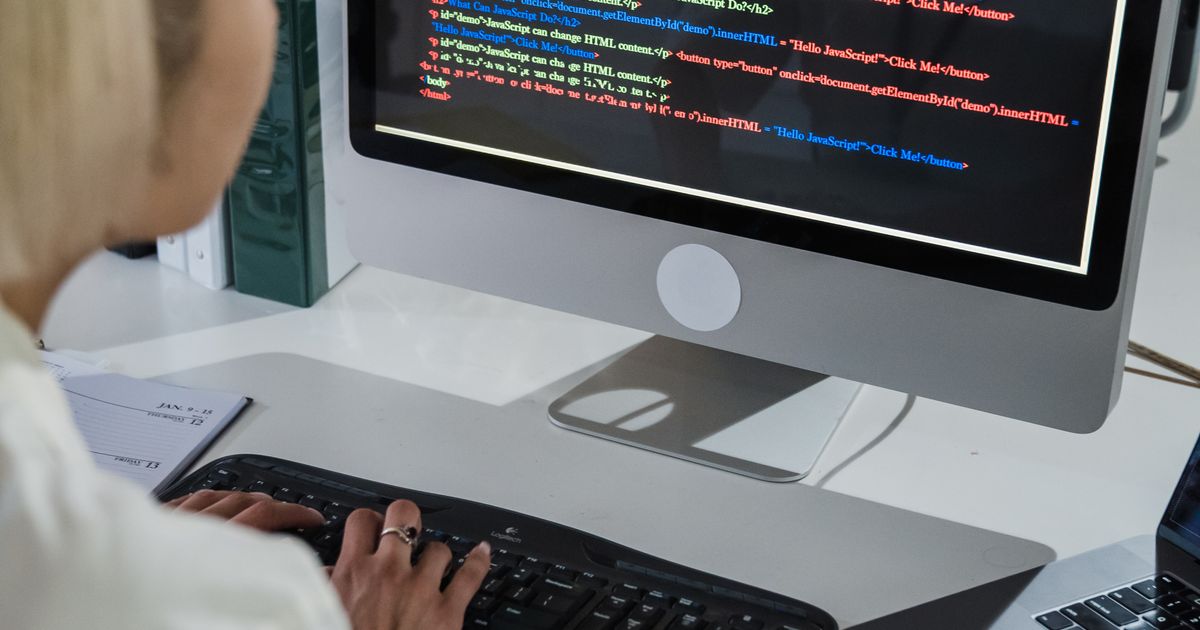 Medical coder working at a computer with coding references